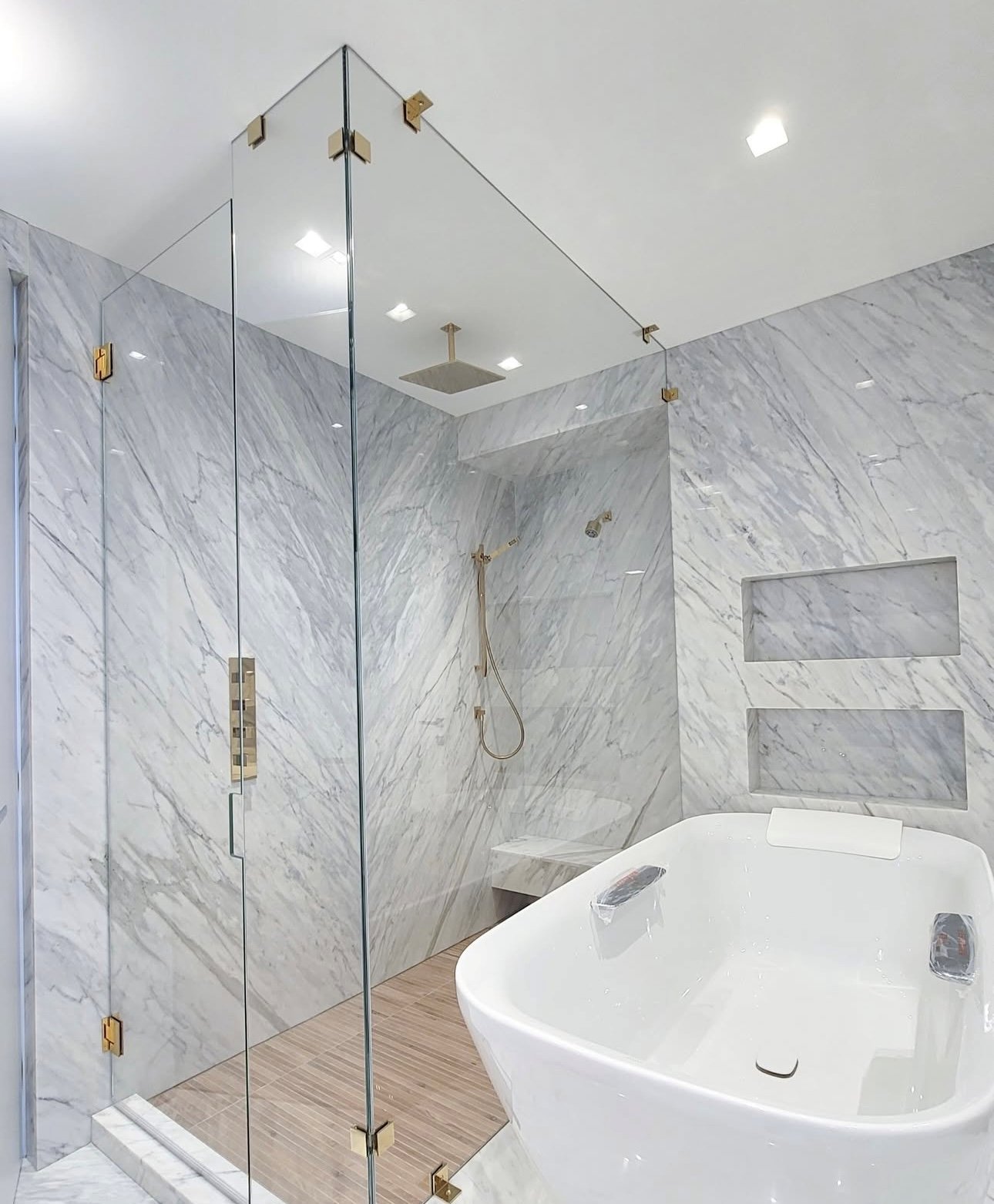 Frameless glass shower with brushed gold hardware overlooking a Miami high-rise skyline