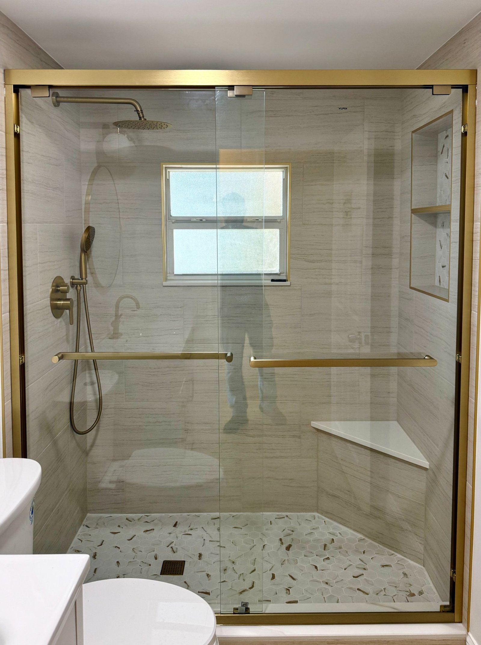 Frameless shower glass with brushed gold hardware and window