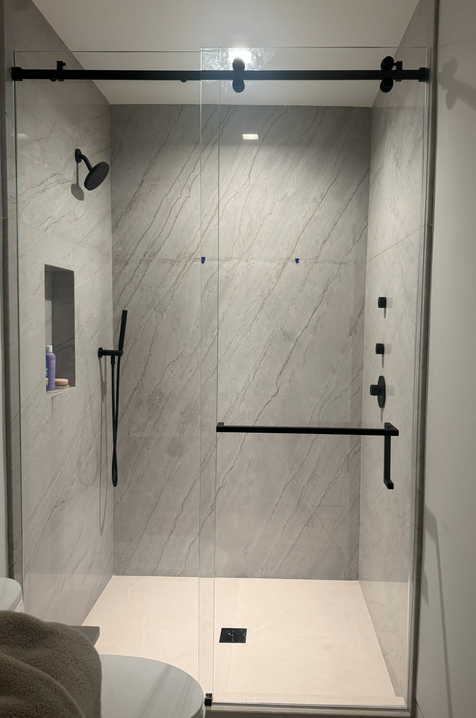 Frameless sliding shower glass with matte black hardware
