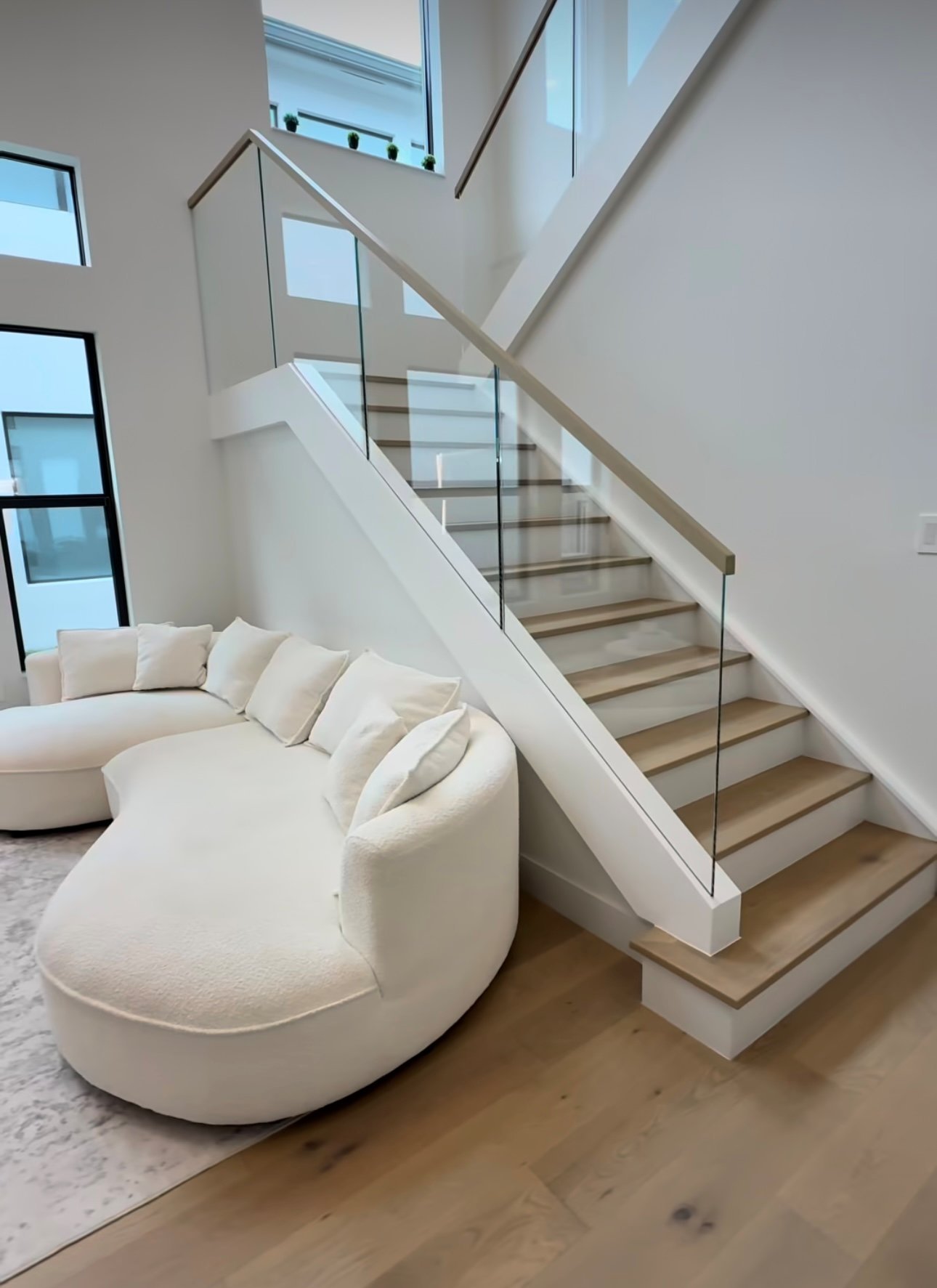 Floating staircase with frameless glass railing and custom wood treads in a South Florida home by Stratus Glass