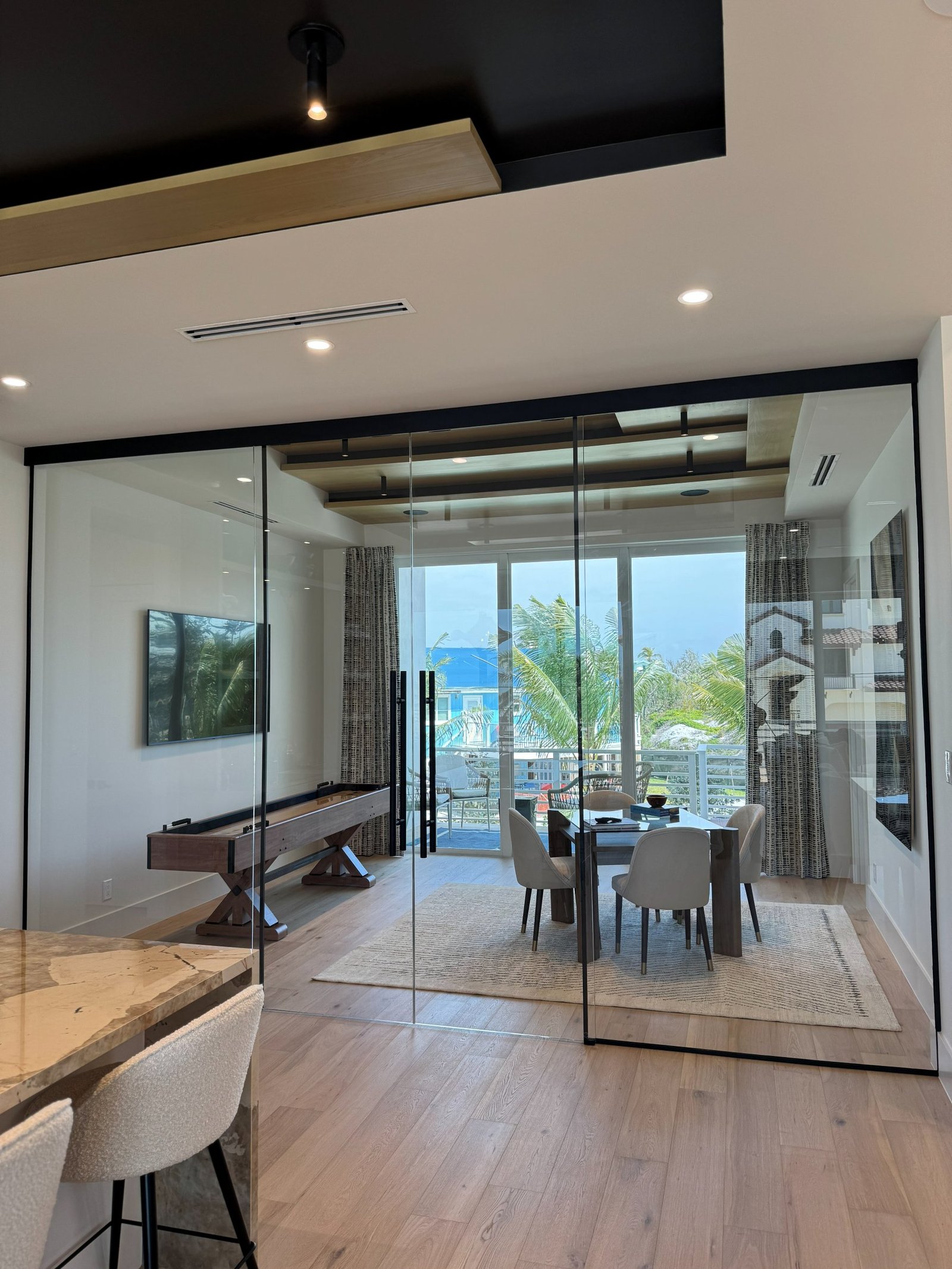 Frameless sliding glass wall partition dividing a modern living space