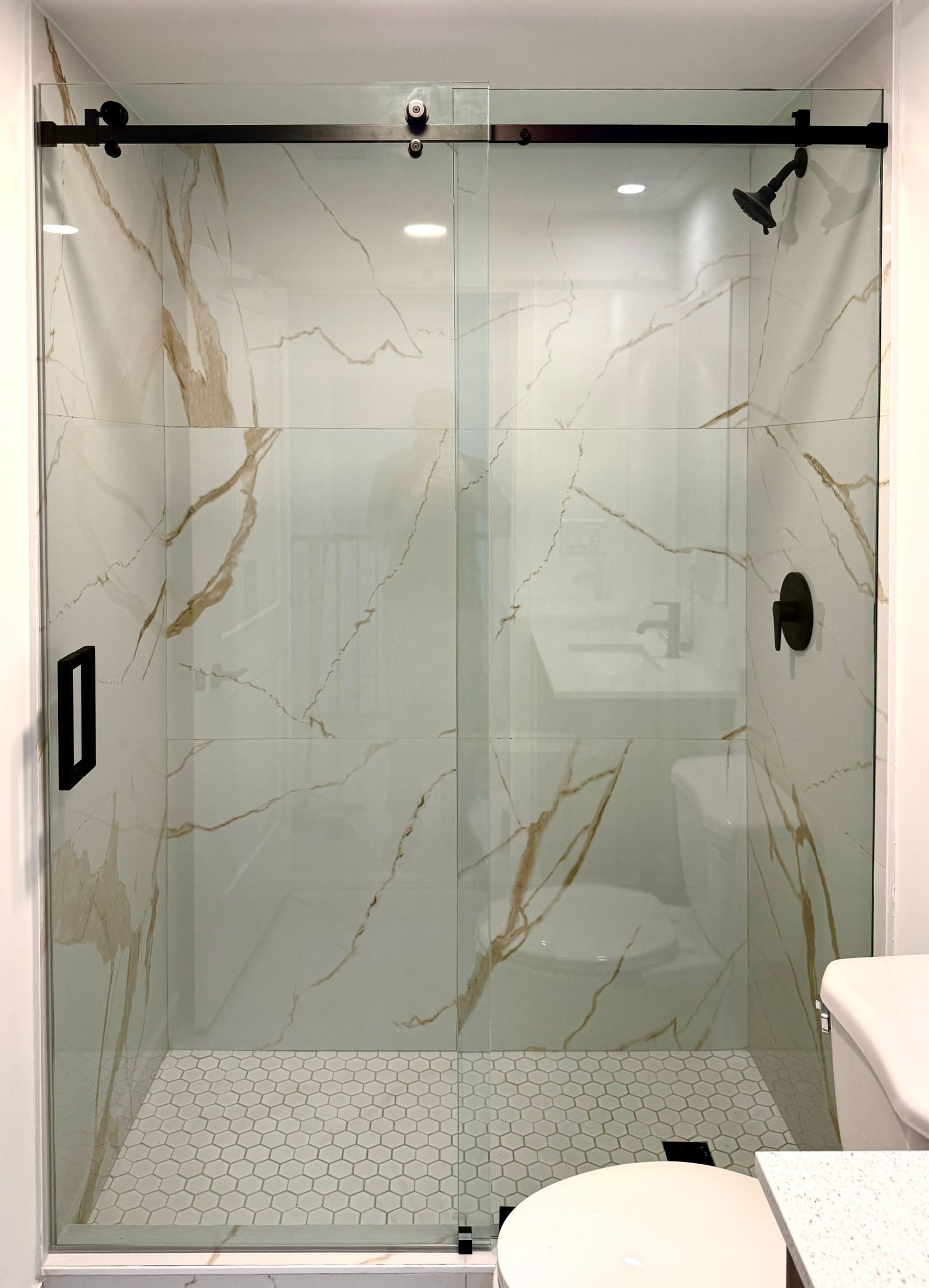 Frameless custom shower glass enclosure with matte black hardware on travertine tile