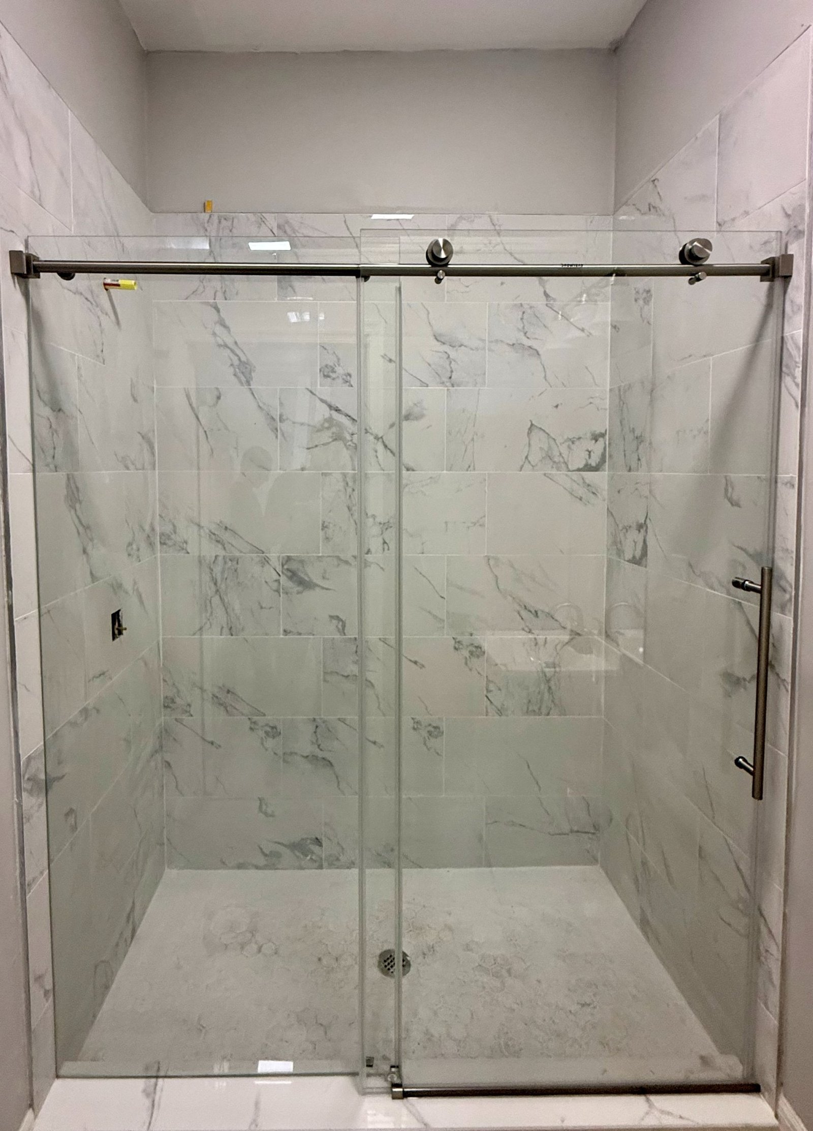 Sliding frameless shower door on marble tile